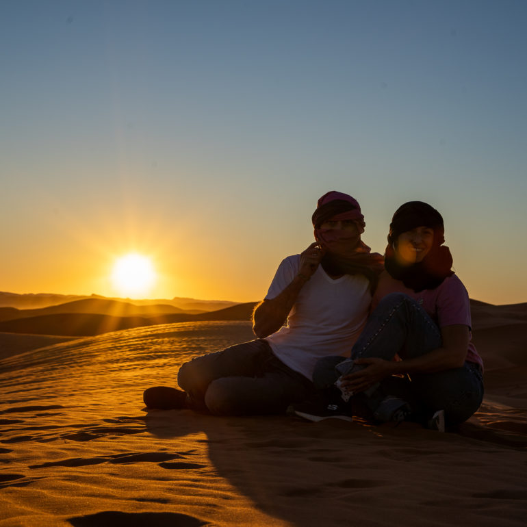 Pareja sentada en el atardecer en el desierto