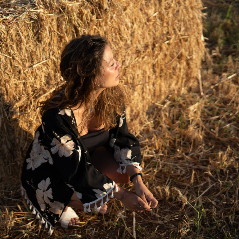 Chica posando frente a bala de paja al atardecer